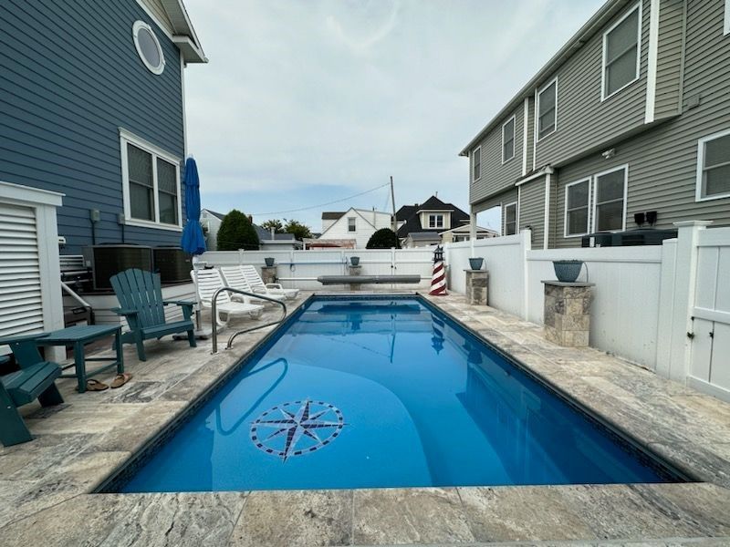 A large swimming pool is in the backyard of a house.