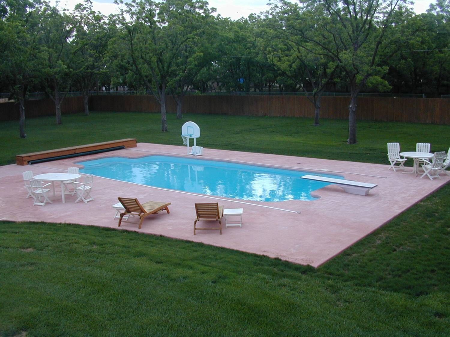 A large swimming pool surrounded by lawn chairs and trees