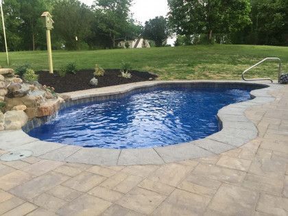 A large swimming pool with a waterfall in the backyard
