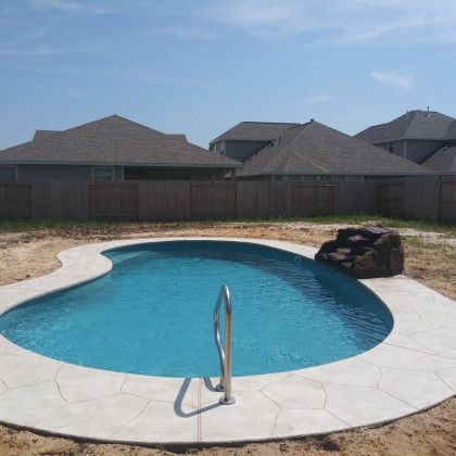 A large swimming pool is in the backyard of a house.