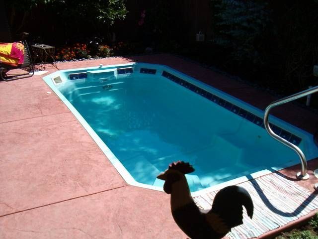 A large swimming pool is sitting on top of a stone patio.
