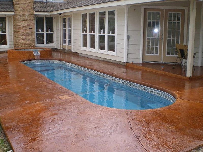 A large swimming pool is in the backyard of a house.