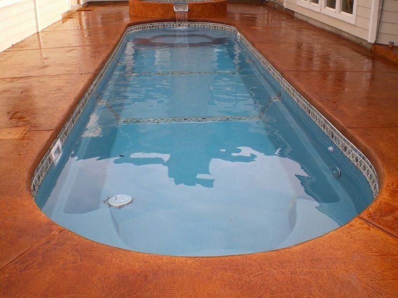 A large swimming pool is sitting on top of a concrete deck.