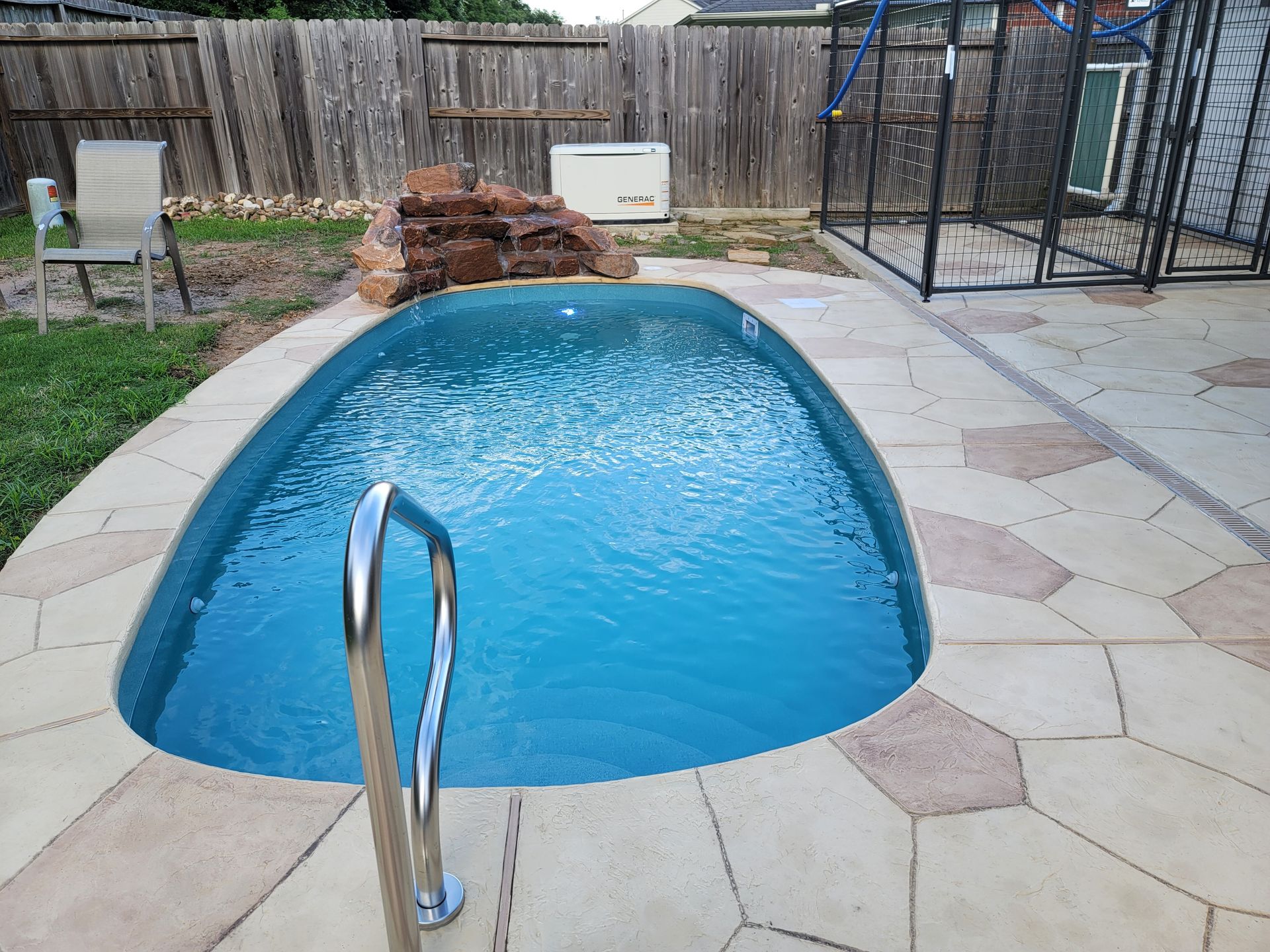 A large swimming pool with stairs leading to it in a backyard.