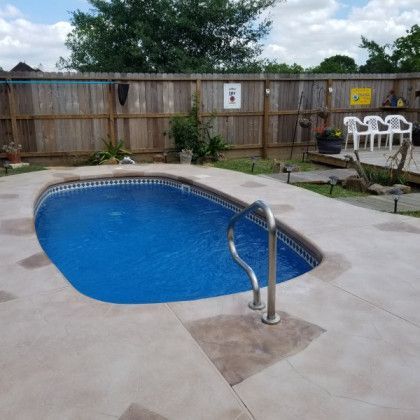A swimming pool in a backyard with a wooden fence in the background