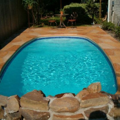 A swimming pool with a table and chairs in the background