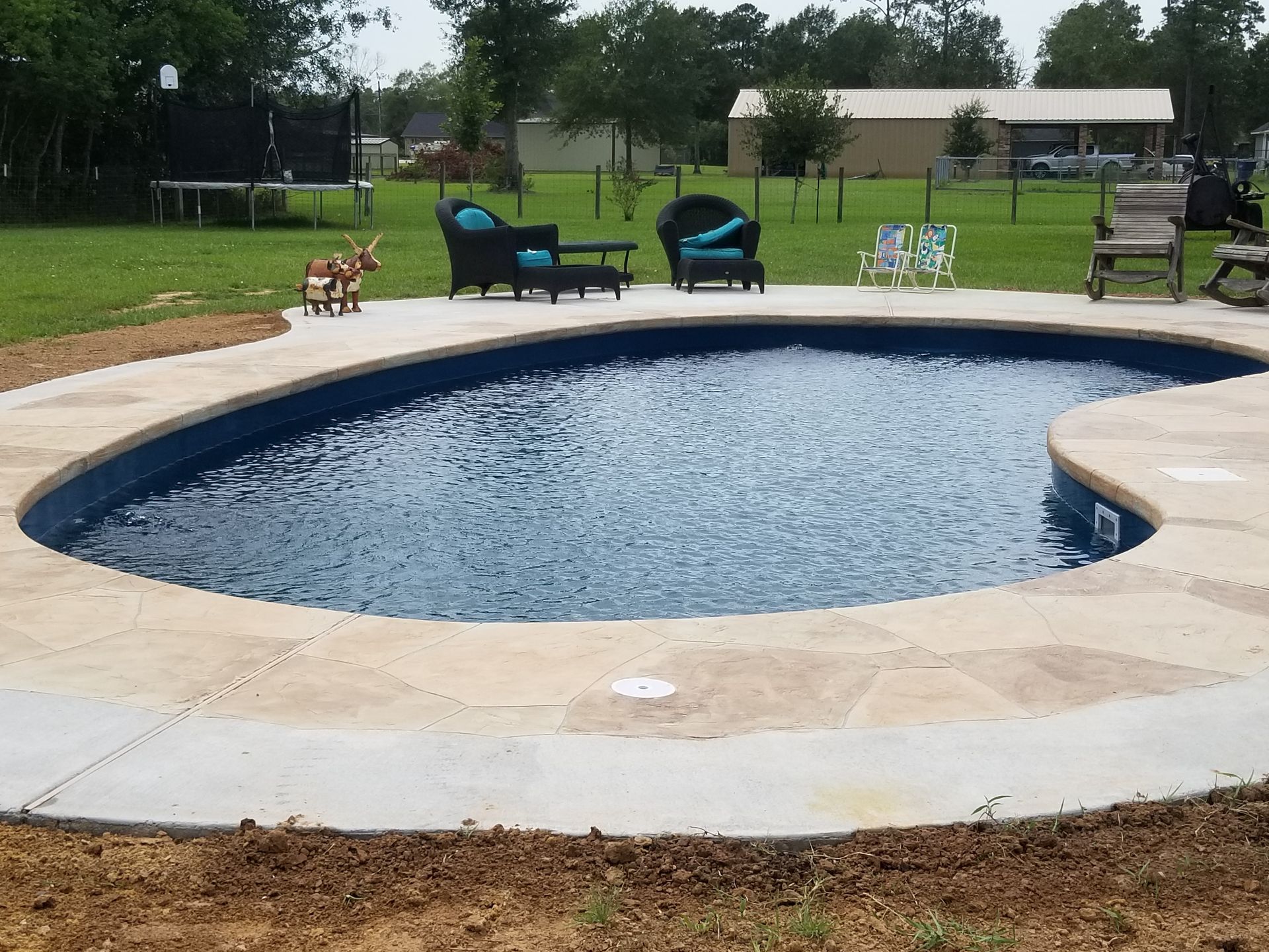 A large swimming pool with two lounge chairs in front of it