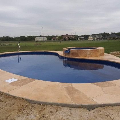 A large swimming pool with a hot tub in the middle of it.
