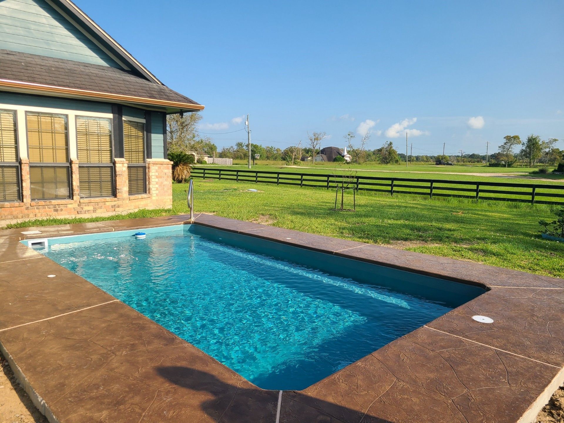 A large swimming pool in a backyard with a wooden fence surrounding it.