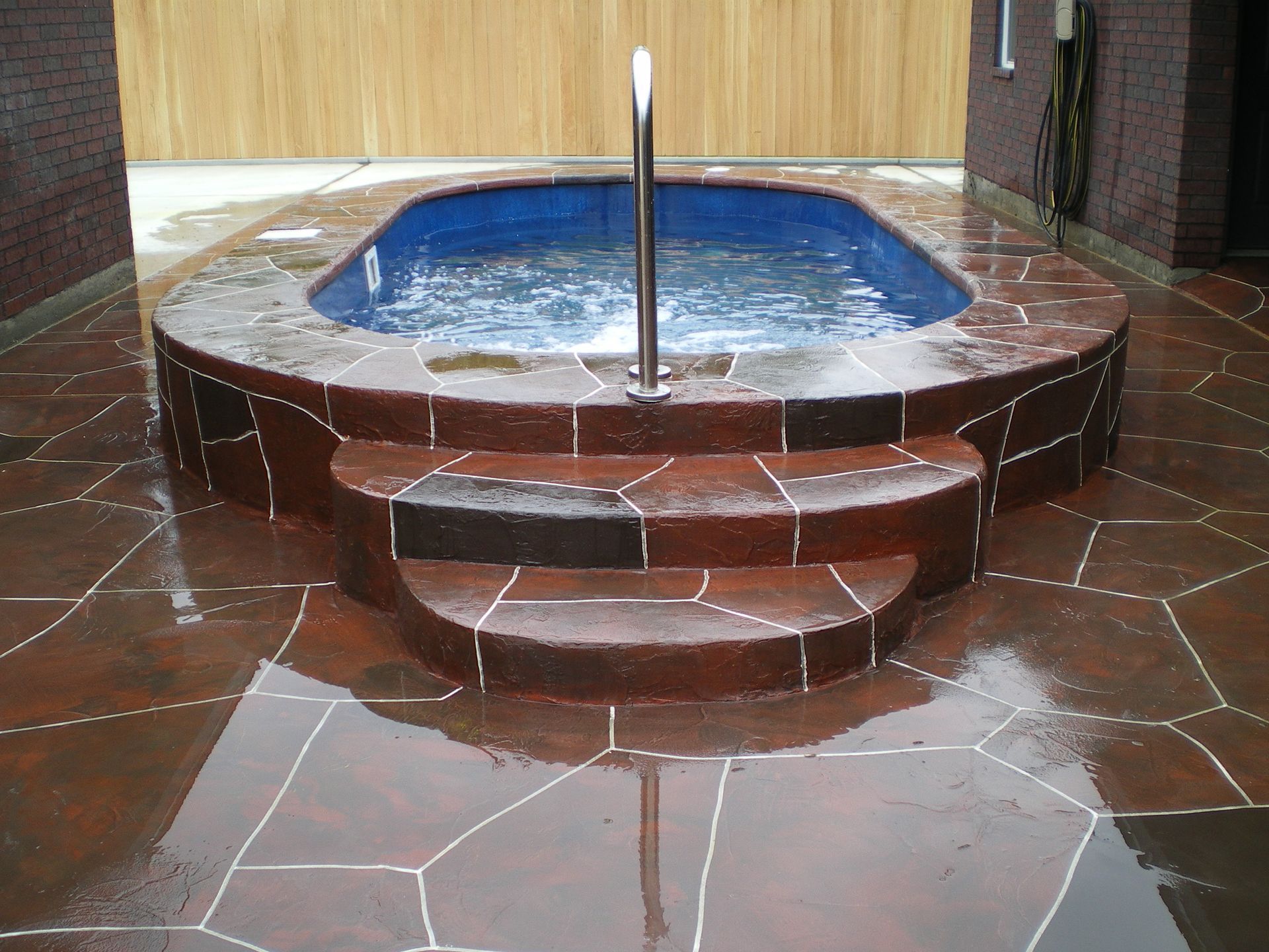 A large swimming pool is sitting on top of a tiled patio.