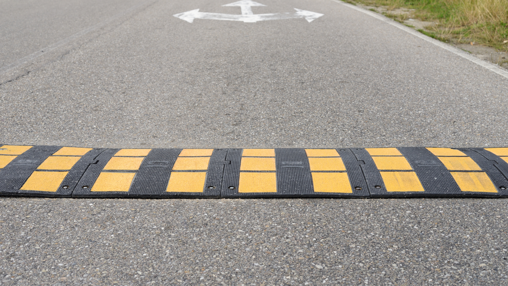A yellow and black speed bump on the side of a road.