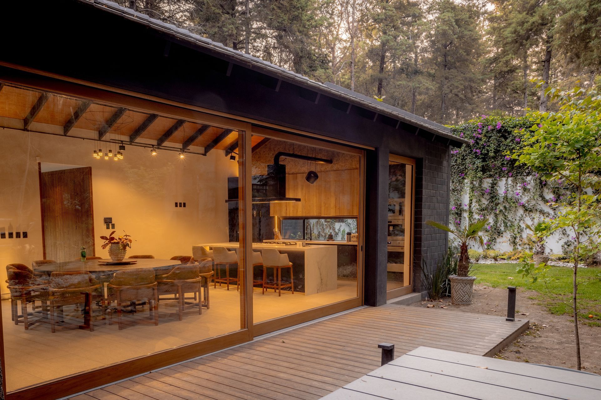 Modern dining area with wooden table, chairs, pendant light, and bedroom nook by bright windows
