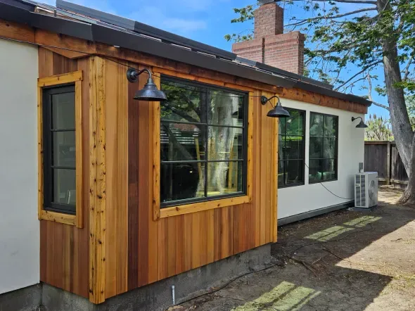Exterior of house with cedar siding, black windows, and black light fixtures.