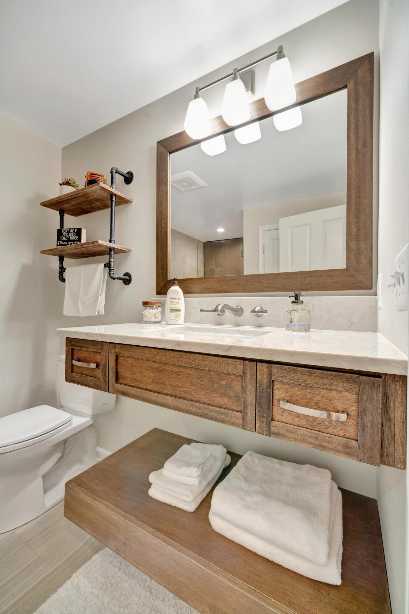 Basement bathroom with a floating wood vanity, a marble-look top, and a wall-mounted faucet.