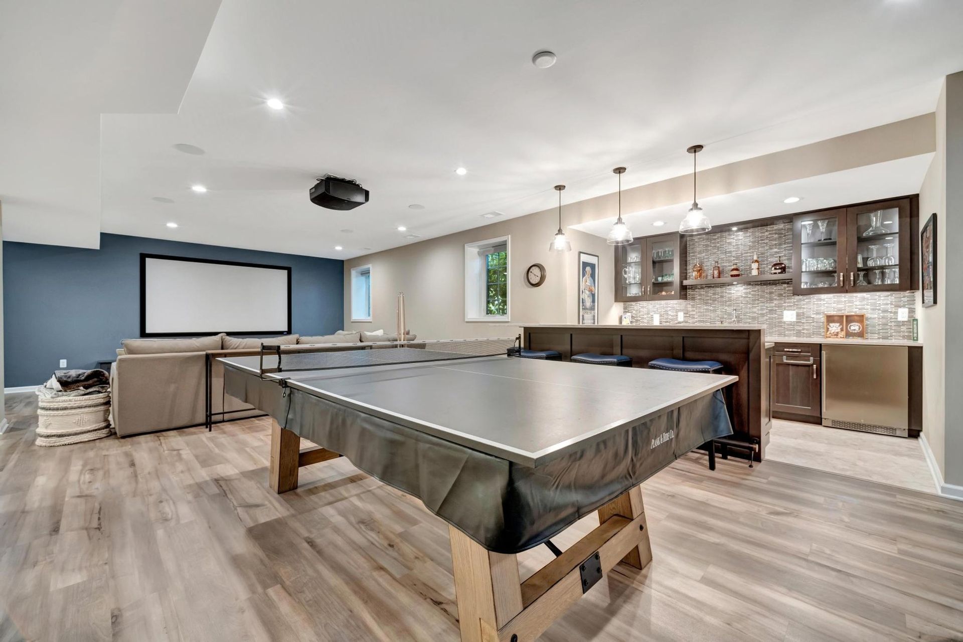 Finished basement with a game area, a projection screen wall, and a wet bar.