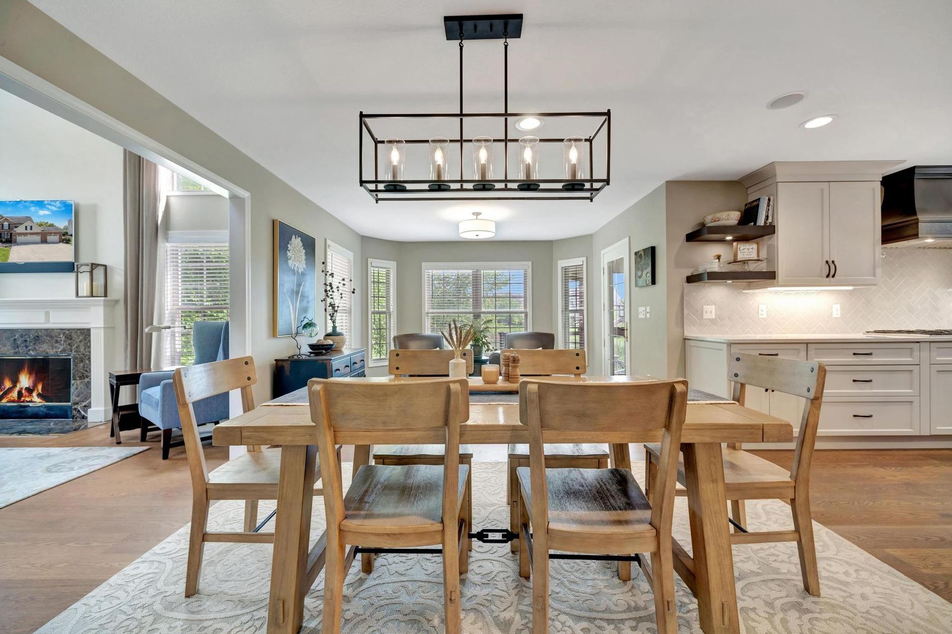 Breakfast area with a black rectangular chandelier and bay windows, open to the kitchen and great room.
