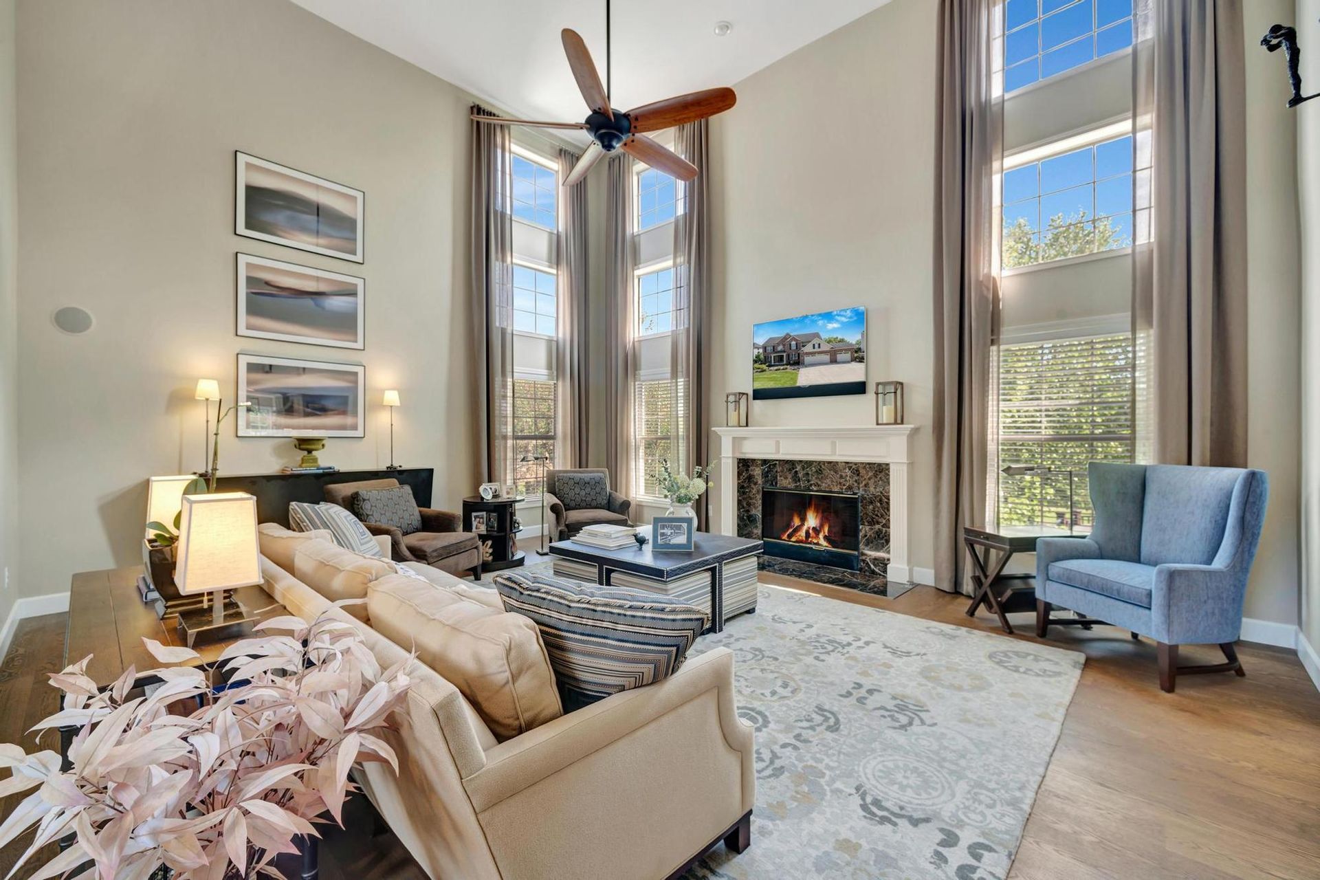 Two-story great room with a fireplace, tall windows, and new wide plank white oak flooring.