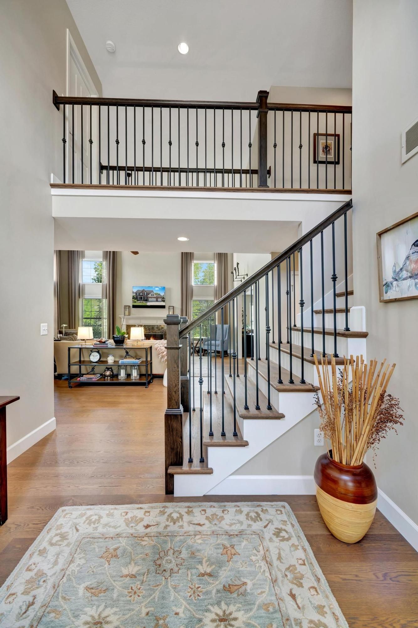Rebuilt foyer staircase with white oak treads, white risers, black steel balusters, and a stained newel post.