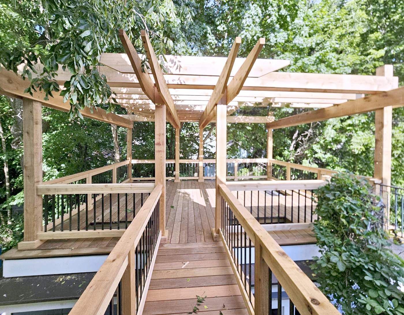 Ipe catwalk with cedar railings leading from the house to a roof deck under a cedar pergola.