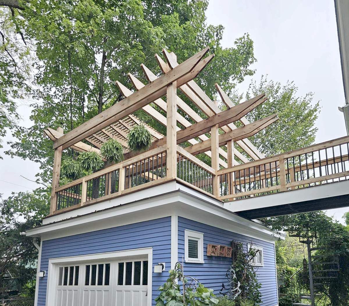 Detached garage with a roof deck on top, cedar railings with black balusters, and a cedar pergola above.