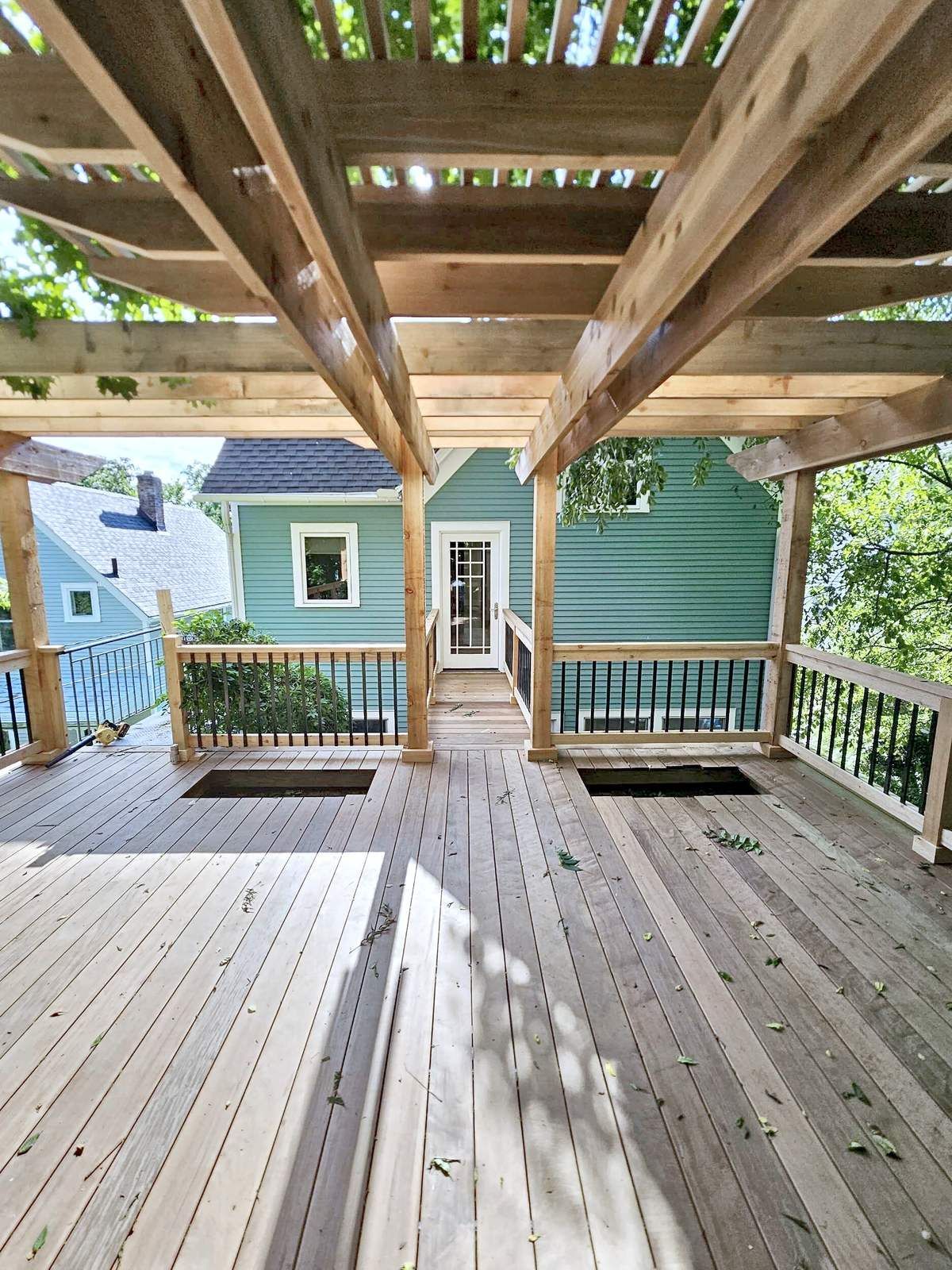 Ipe roof deck under a cedar pergola, looking back toward the house and the catwalk door.