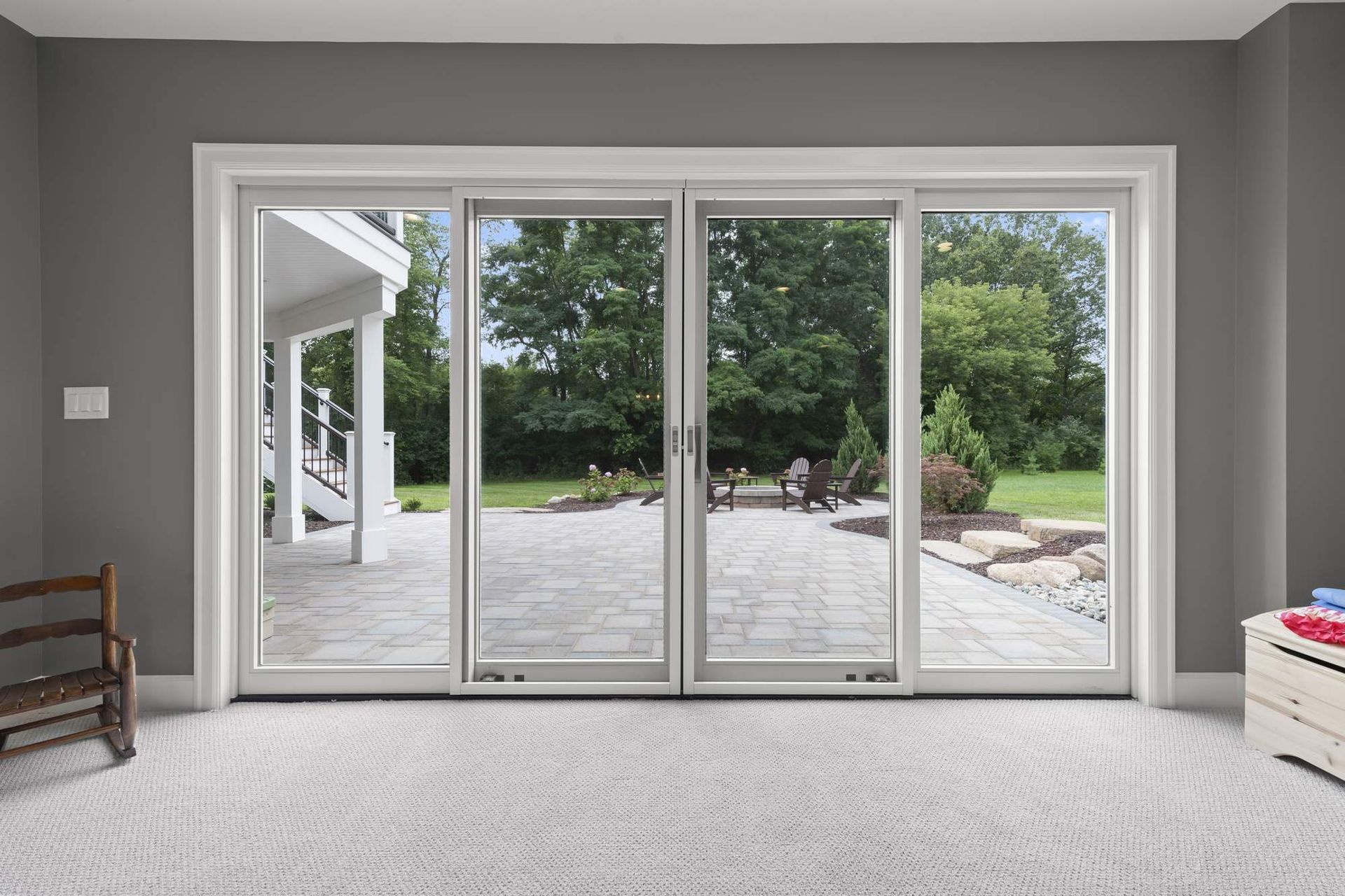 Basement glass door wall opening onto a paver patio and backyard.
