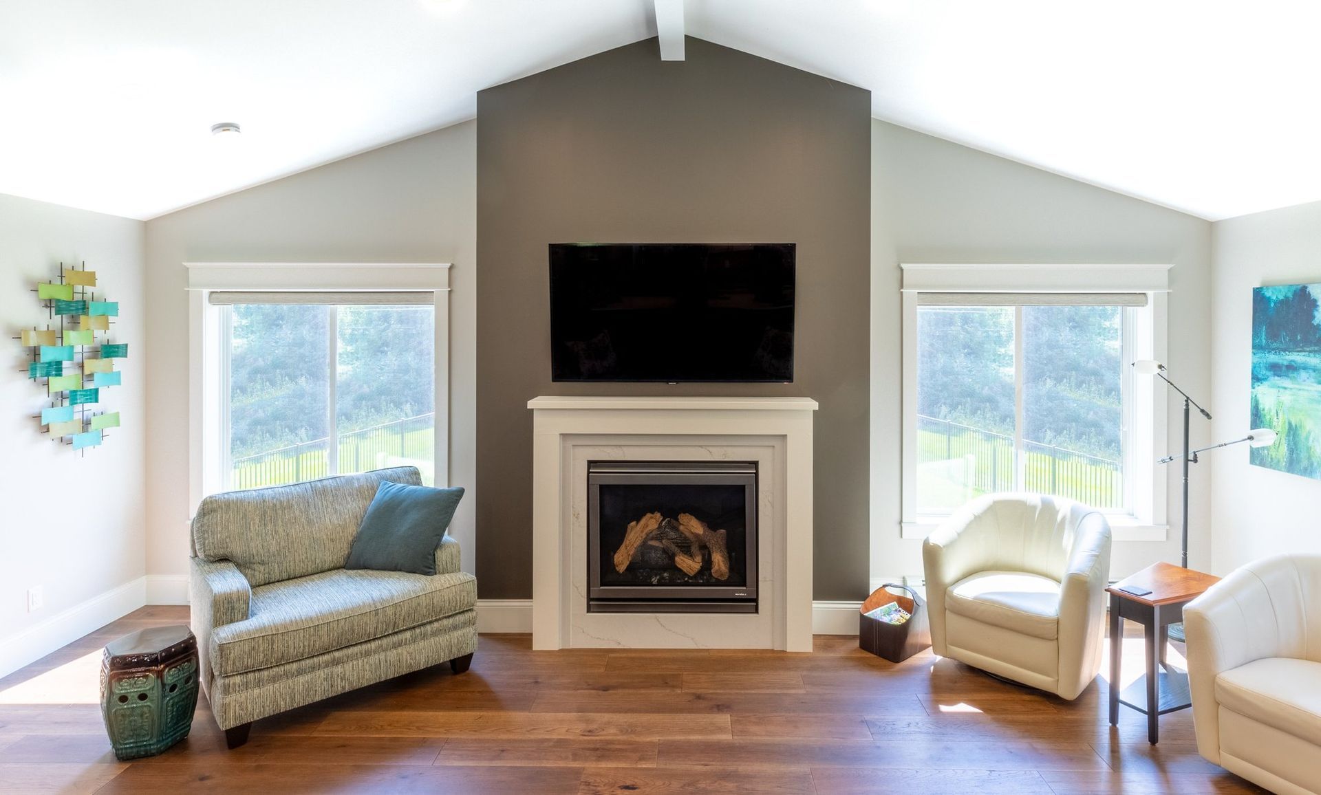 Vaulted family room addition with a gas fireplace, dark gray accent wall, and windows on both sides looking out to the yard.