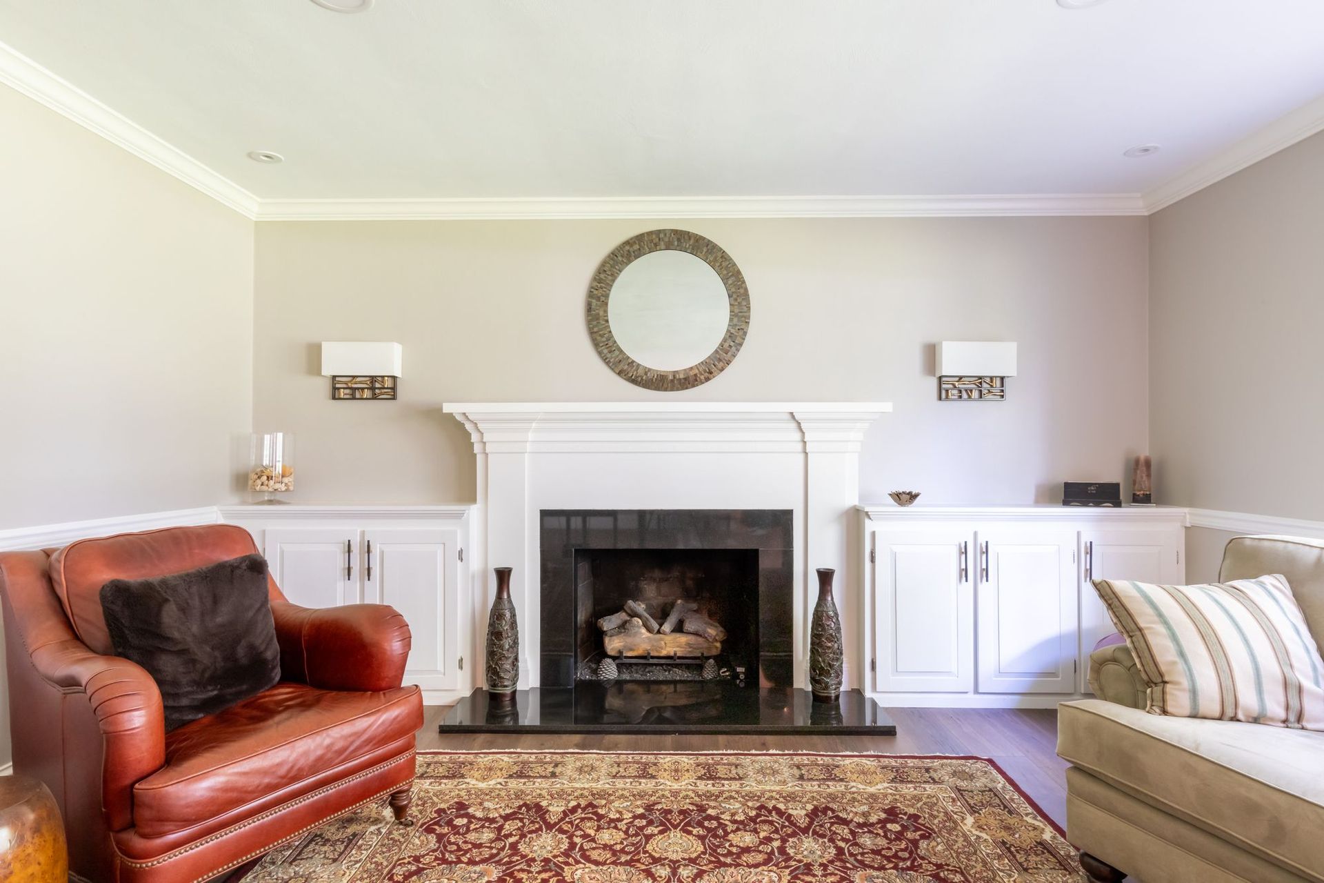 Front living room fireplace with a white painted mantel, black granite surround and hearth, and built-in cabinets on both sides.