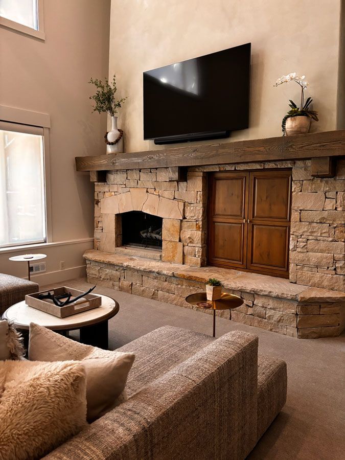Cozy living room with stone fireplace, wall-mounted TV, and brown sofa facing the hearth
