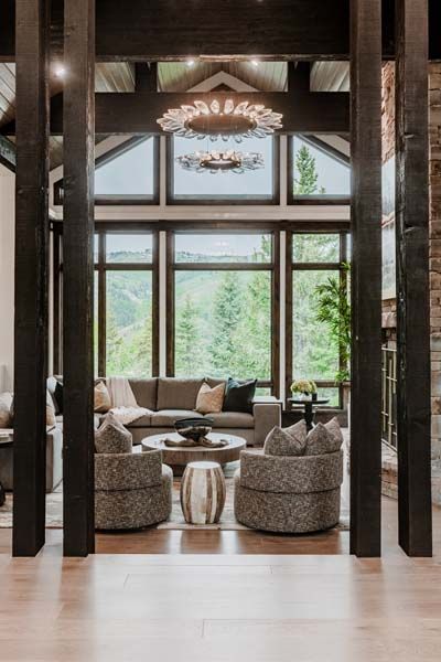 Elegant living room with patterned chairs, sofa, and large windows overlooking a forested view
