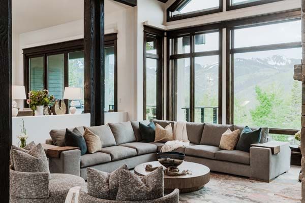 Modern living room with sectional sofa, coffee table, and large windows overlooking mountains