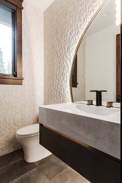 Modern bathroom with white vanity, black faucet, toilet, and a textured accent wall