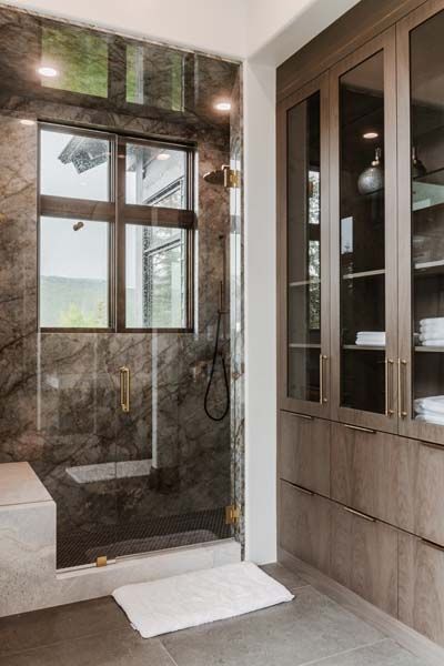 Modern bathroom with a marble walk-in shower, glass door, and built-in wooden cabinets