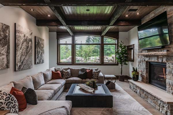 Modern living room with large sectional sofa, fireplace, wall-mounted TV, and mountain view through windows