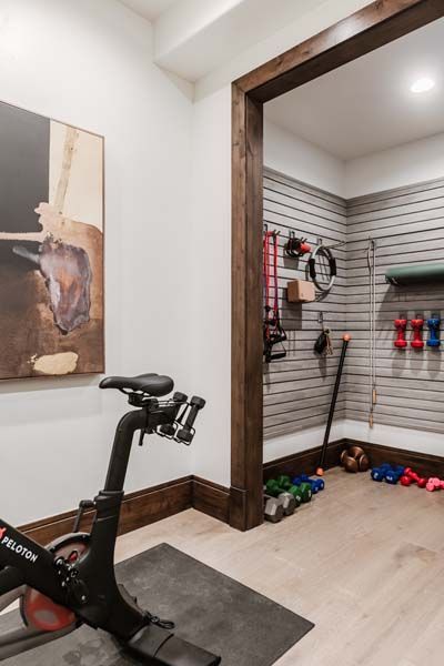 Home gym corner with stationary bike, wall art, and slatwall display with fitness accessories