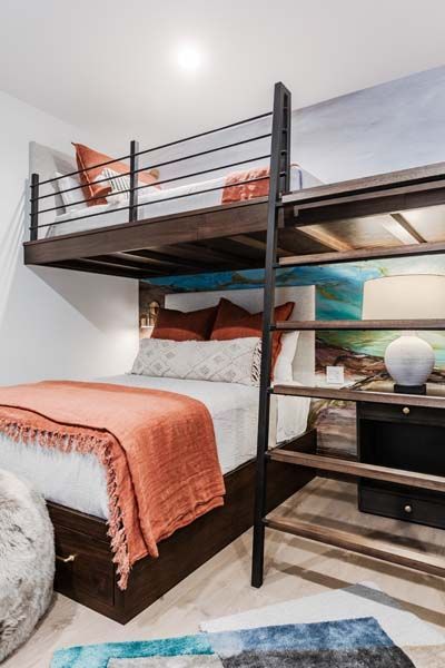 Loft bed with a black metal frame, coral bedding, and stairs in a bright modern bedroom