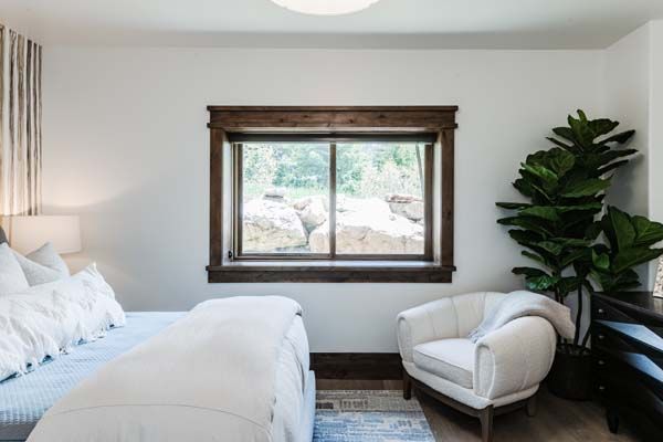 Bright bedroom with a white bed, window seat, and leafy plant by the window