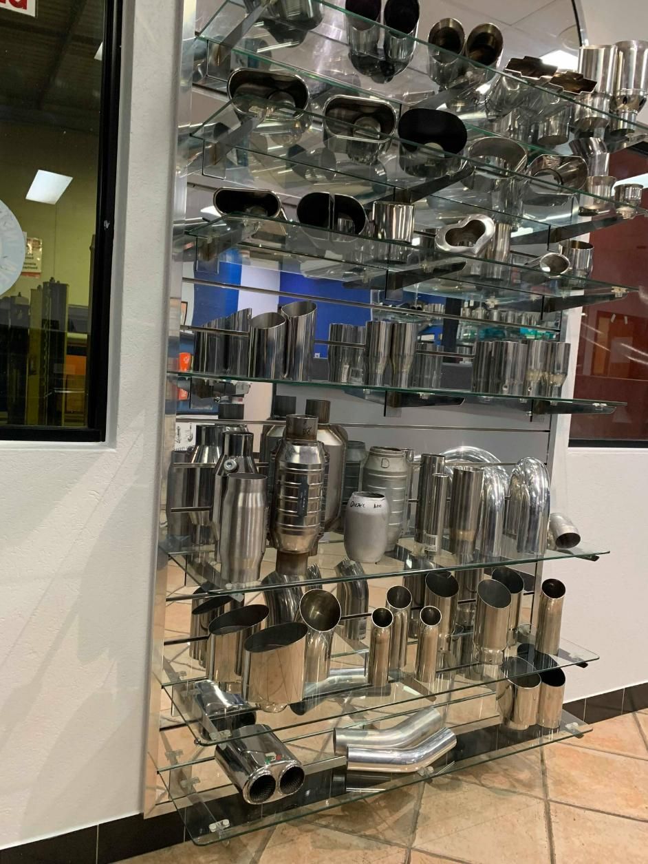 A Display Case Filled with A Variety of Stainless Steel Exhaust Pipes — Carline Automotive Solutions in Bungalow, QLD