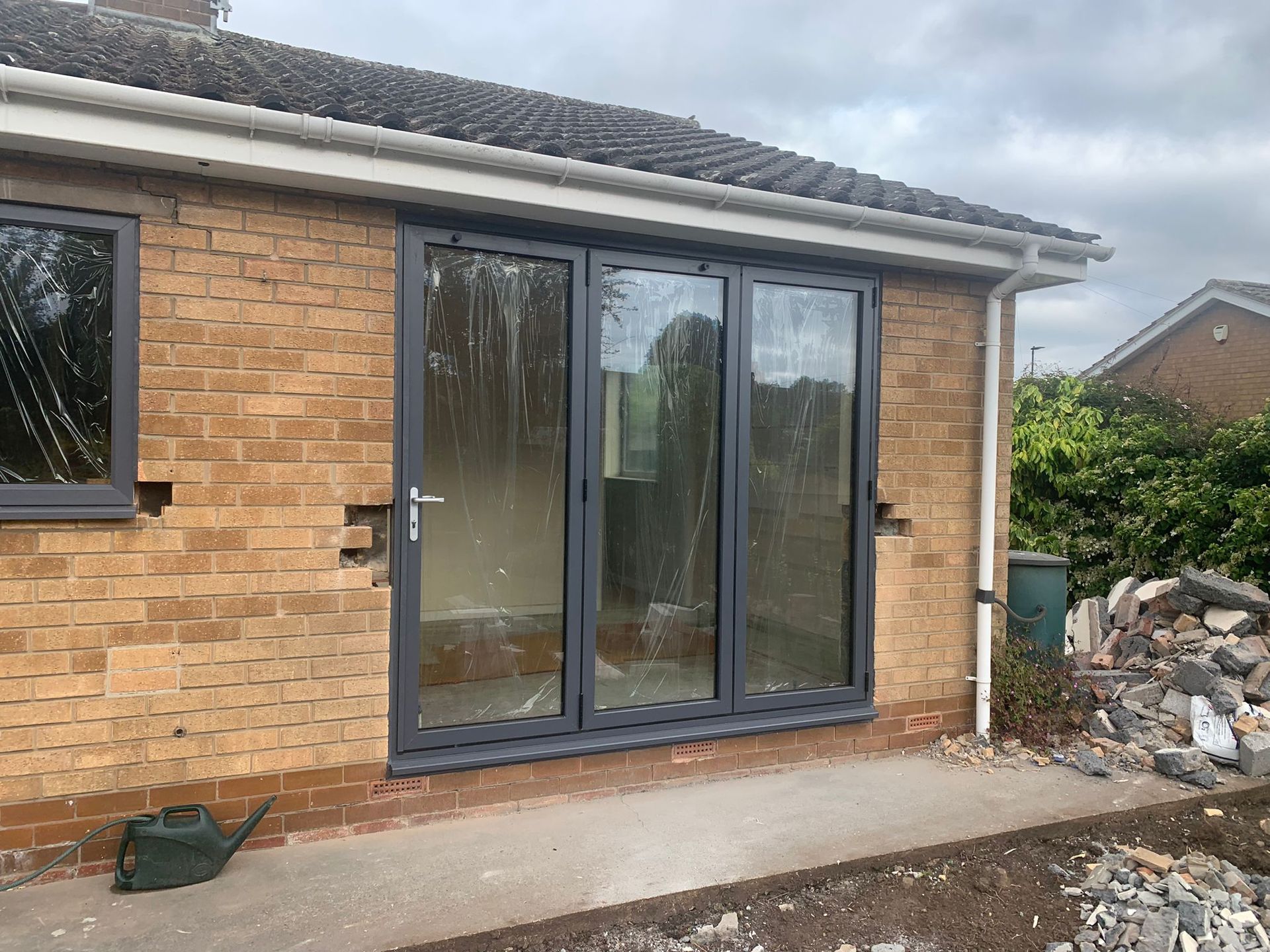 Brick house patio with dark sliding glass doors and some construction debris beside it