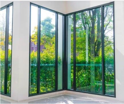 Corner view of glazed bifold doors opening to reveal a scenic garden, allowing natural light to flood the interior space.