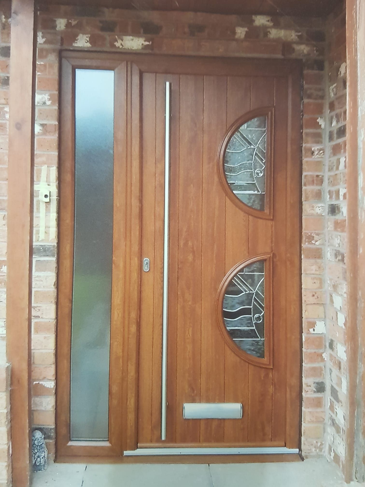 Wooden front door with frosted glass panels set in a brick entryway