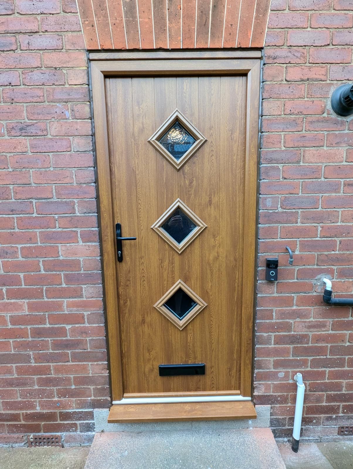 Wooden front door with three diamond windows in a brick wall