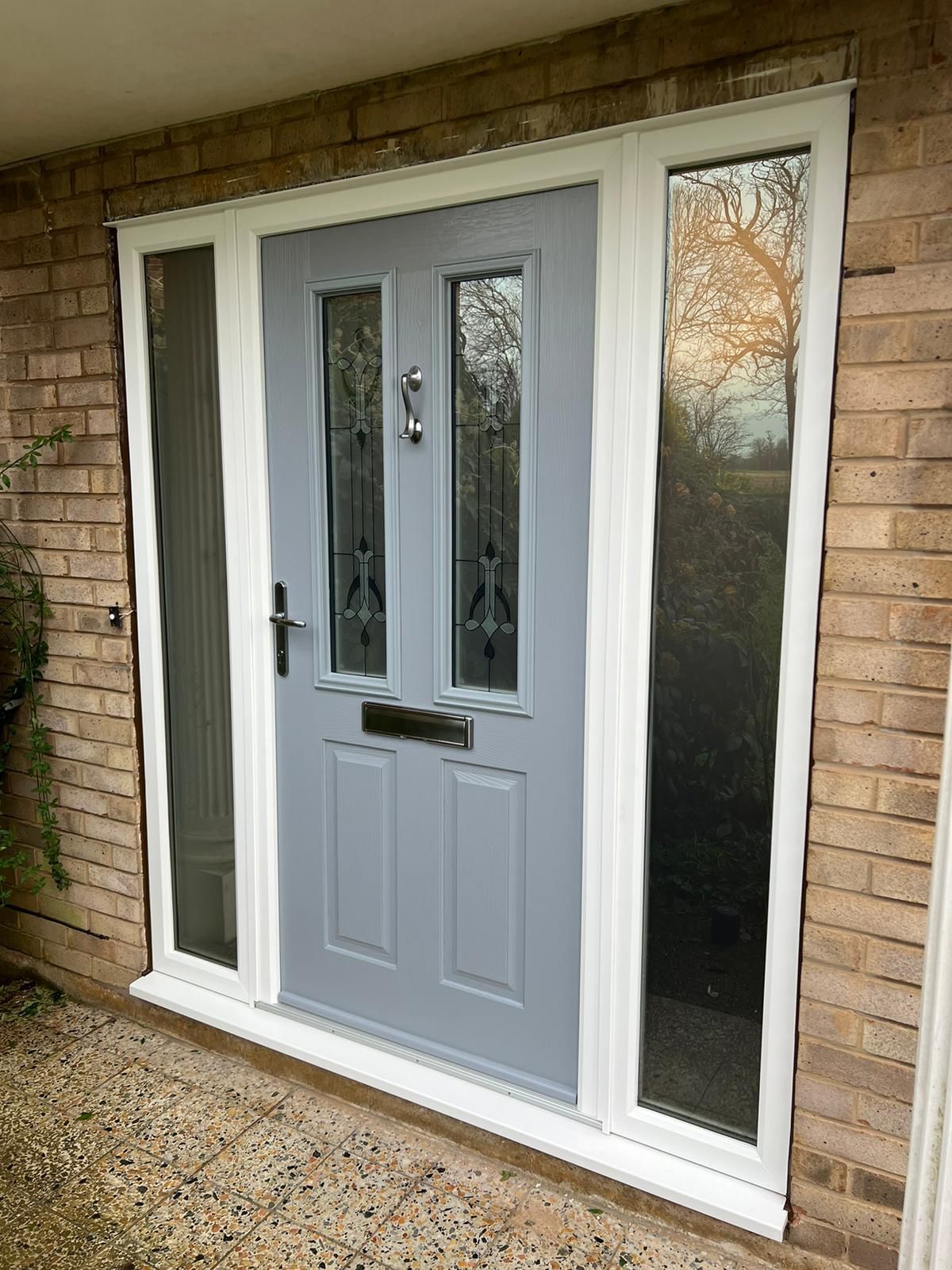 Gray front door with sidelights in a brick house entryway