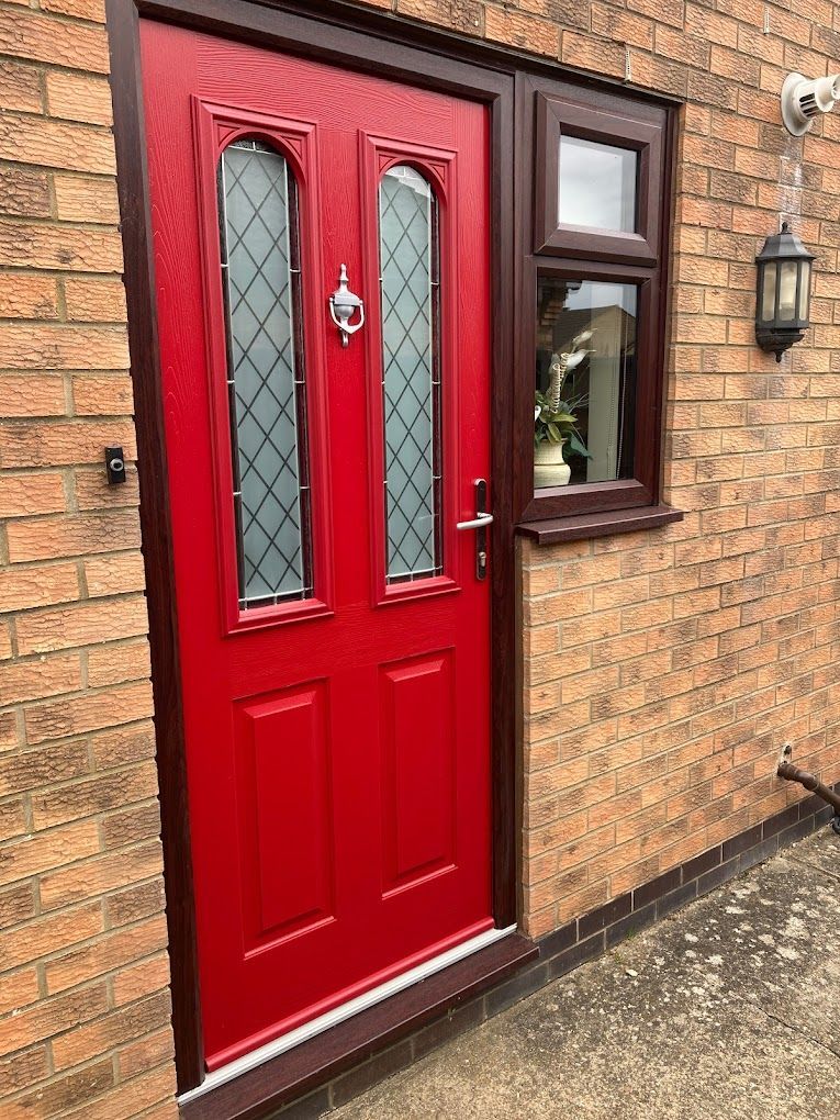 Bright red front door with frosted glass panels set in a brick house wall