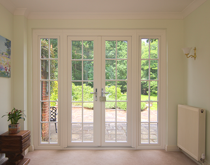 Bright living room with French doors opening to a green garden and patio outside.