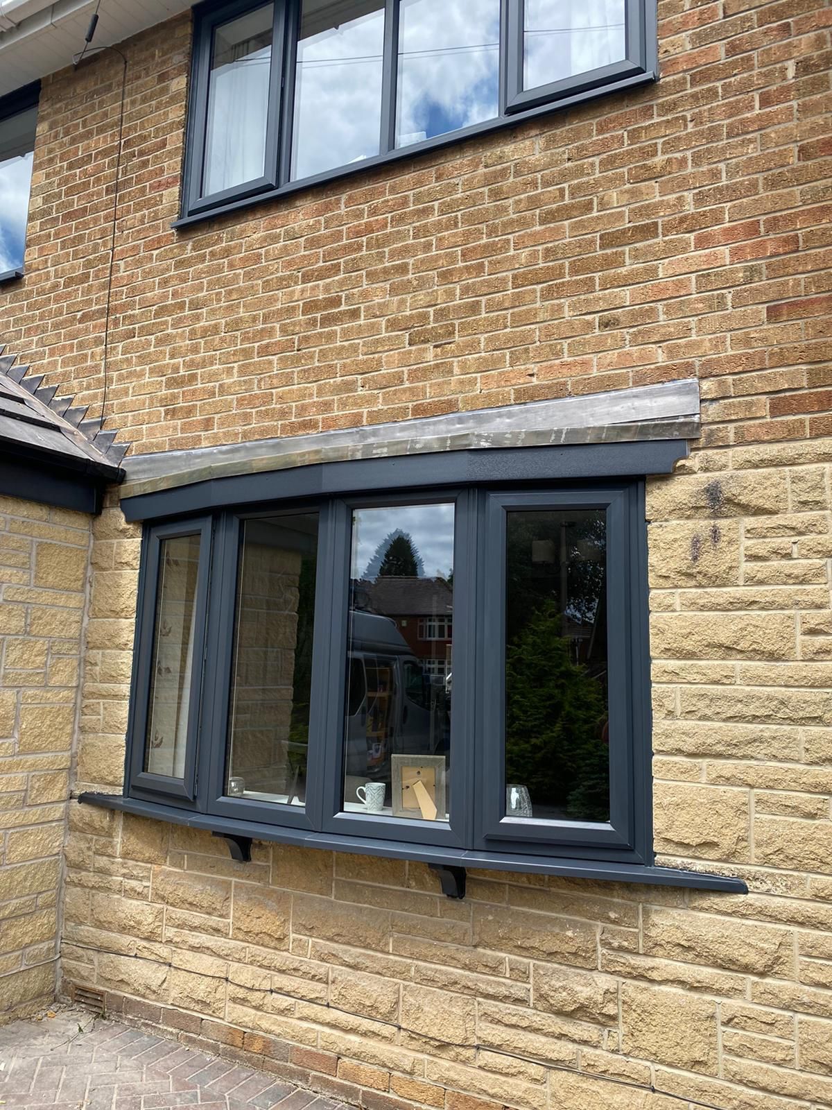 Black-framed bay window on a brick and stone house exterior