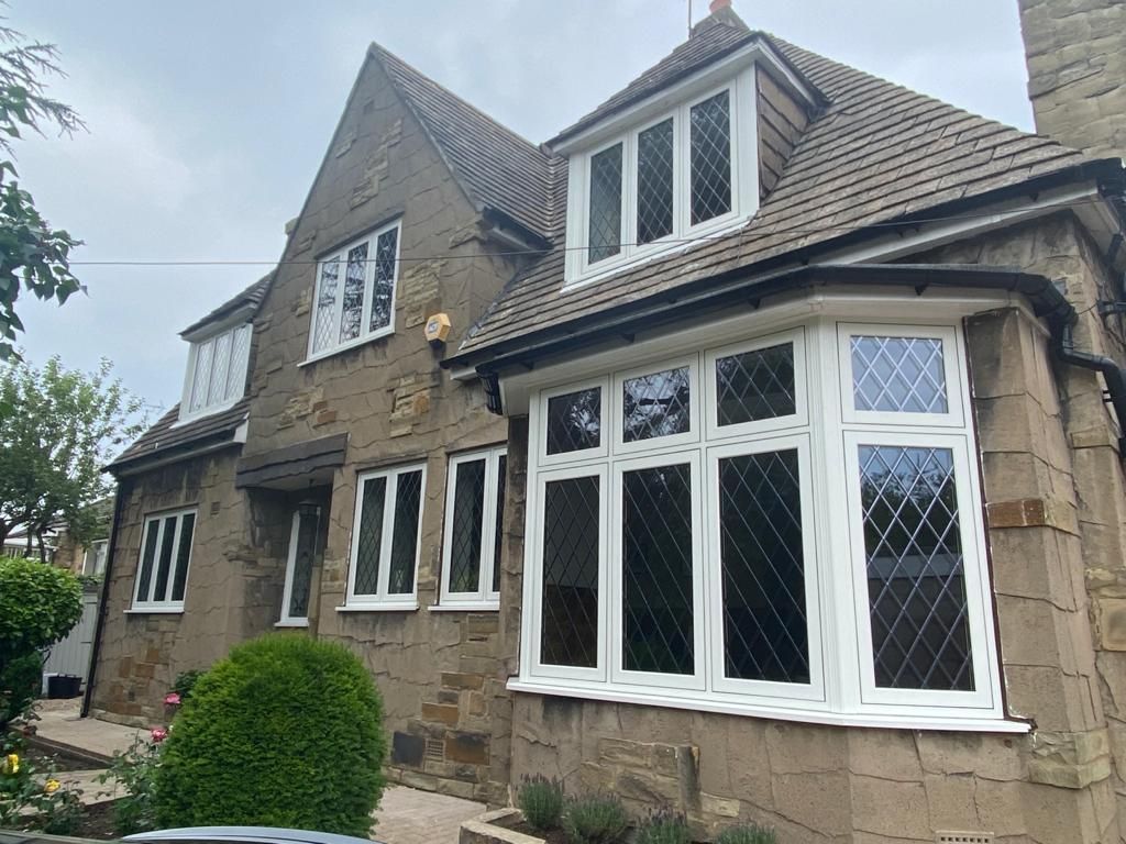 Stone house with white bay windows and a tiled roof, seen from the front garden