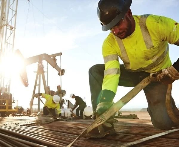Construction workers pouring concrete on a rebar foundation at a worksite, one kneeling in the foreground.