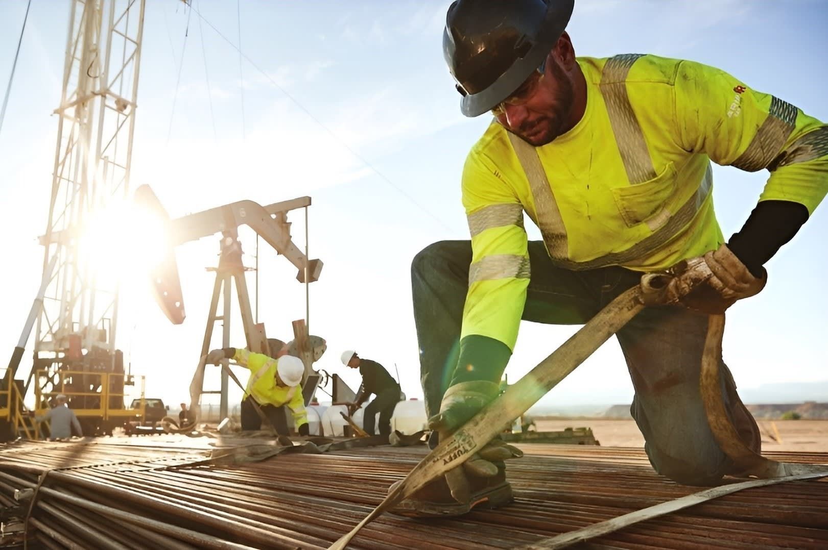 Construction workers in hard hats and neon safety gear smoothing wet concrete at a job site.