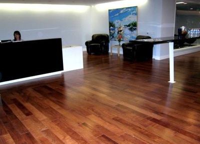 A woman is sitting at a desk in a lobby with a wooden floor.